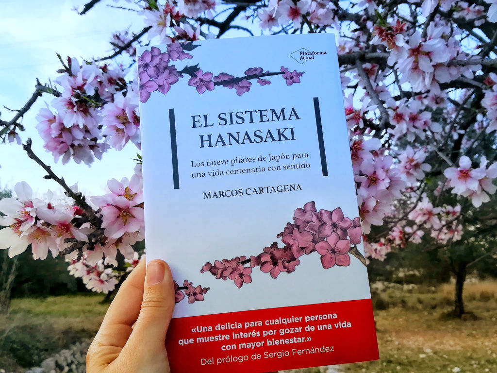 Portada junto a flores de almendro del libro "El sistema Hanasaki", de Marcos Cartagena, editado por Plataforma Editorial